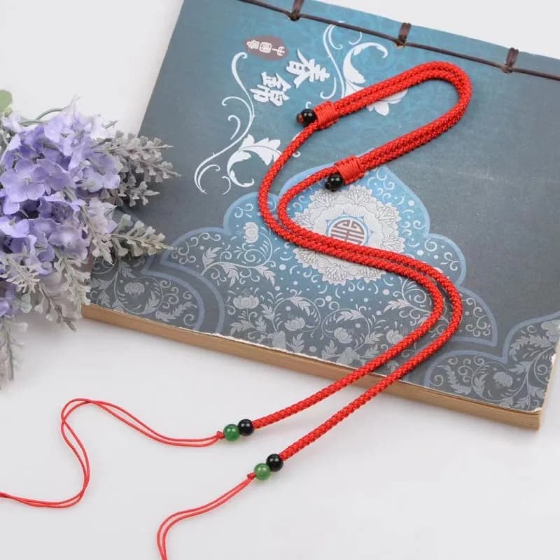 Collier pendentif avec perles Dzi attachées à un cordon, portées sur la clavicule